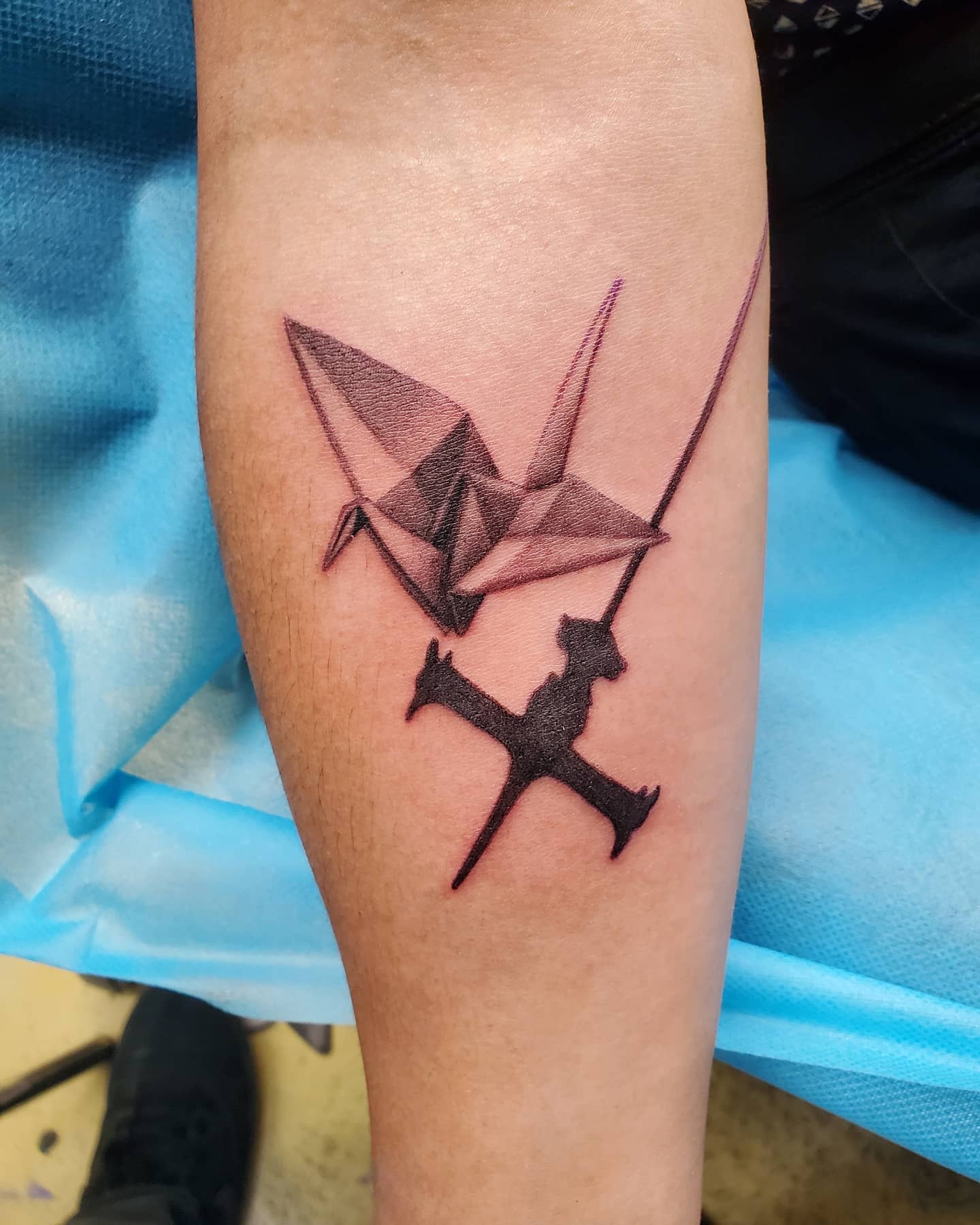 Minimalist tattoo featuring a black origami crane and the silhouette of a spaceship from Cowboy Bebop